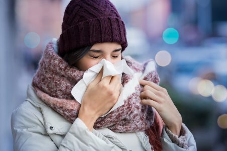 Sick woman blows nose outdoors